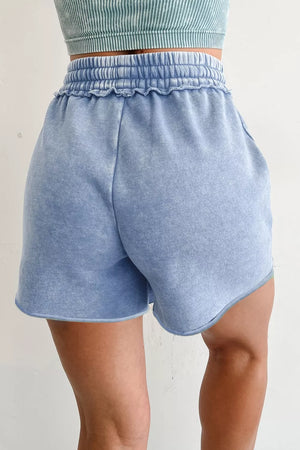 Light blue acid-washed cotton drawstring shorts with pockets and ruffled elastic waistband.