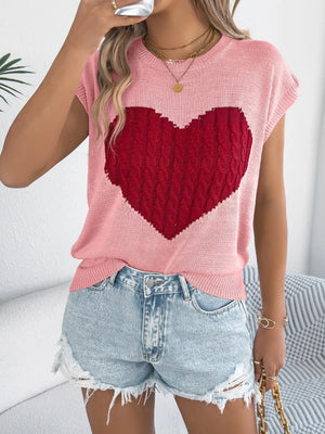 Blush pink cable knit sweater vest with a red cable knit heart graphic and cap sleeves.