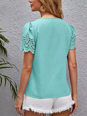 Aqua v-neck blouse with cutout lace detail on short sleeves and ruffled cuffs.