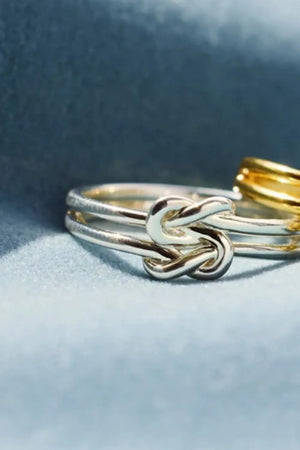 Double band knot ring in silver with a gold ring in the background