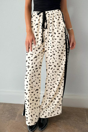 Maternity leggings in cream with black abstract leopard print, drawstring waist, and side stripe detail.