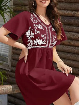 Burgundy embroidered floral v-neck mini dress with flutter sleeves and smocked waist.