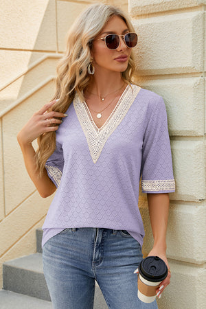 Lavender textured V-neck blouse with lace trim and short sleeves.