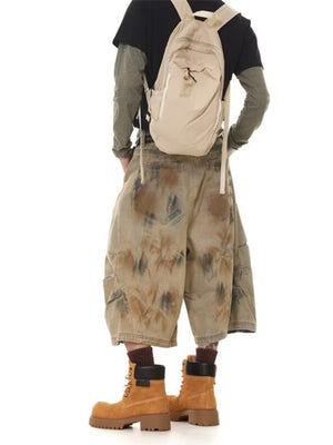Men's vintage wash wide-leg denim shorts in beige with a distressed pattern and cargo pockets.