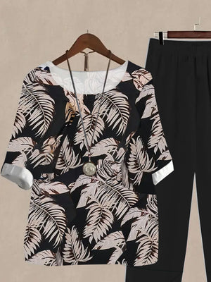 Floral print half sleeve top and black pants set with white cuffs and neckline.