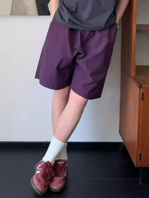 Men's purple lightweight drawstring shorts with pockets, styled with white socks and sneakers.