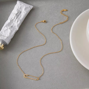 Gold layered necklace with a diamond-accented paperclip pendant.