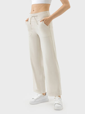 Cream wide-leg drawstring active trousers with pockets and a relaxed fit.
