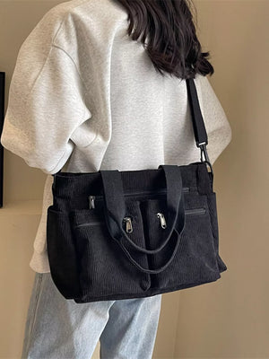 Textured black corduroy crossbody bag with multiple zippered pockets and adjustable strap.