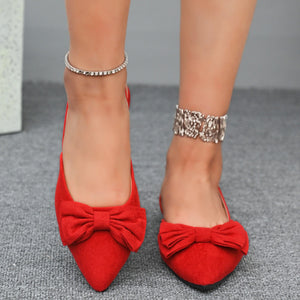 Red bow-embellished slingback flats with pointed toes and ankle bracelets.
