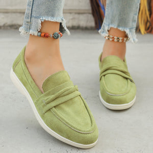 Green suede slip-on loafers with a round toe and decorative knot detail.