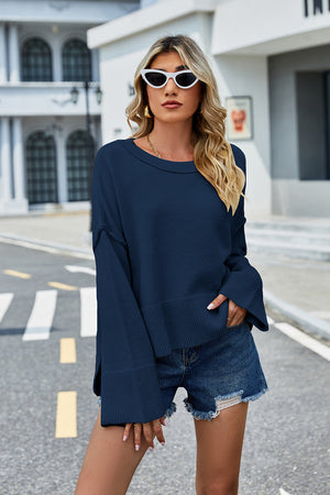 Navy acrylic knit sweater with flared sleeves and slit hem detail.
