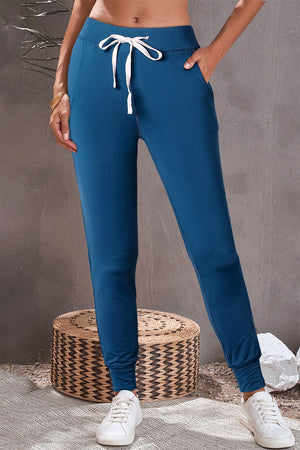 Dark blue slim-fit joggers with white drawstring and cuffed ankles.