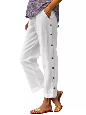 White relaxed fit pants with decorative buttons down the side and pockets.