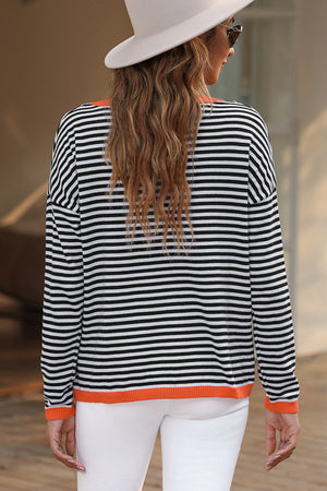 Striped crewneck sweater with contrast orange trim and long sleeves.