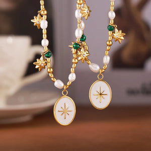 Gold celestial pendant necklace with pearls, starburst charms, and oval white enamel starburst pendants.