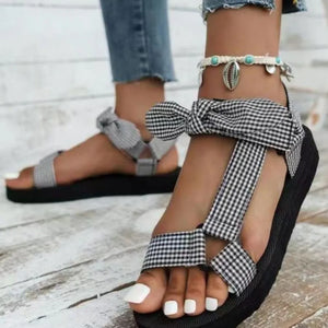 Bow-tie platform sandals in black and white plaid with ankle strap detail.