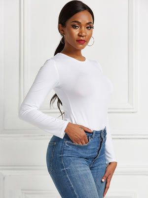 White long sleeve ribbed bodysuit with crew neck, tucked into blue jeans.