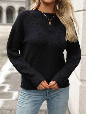 Black cable knit sweater with crew neck and long sleeves.