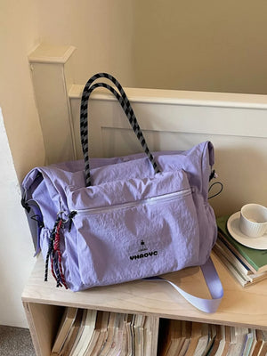 Chic Oxford cloth travel duffel bag in lavender with black and white rope handles and tassel details.