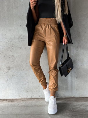 Brown leatherette gathered waist joggers with elastic cuffs and a relaxed fit.