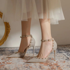 Apricot patent leather studded ankle strap pumps with pointed toe and buckle closure.