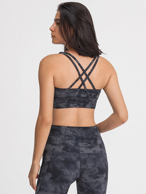 Crisscross back sports bra in dark gray tie-dye pattern with strappy details.