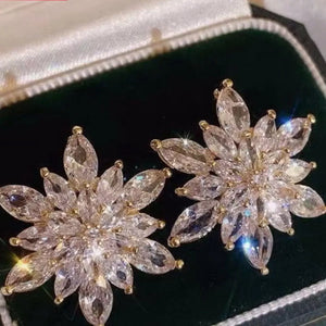 Elegant gold-plated snowflake stud earrings with clear crystal accents.