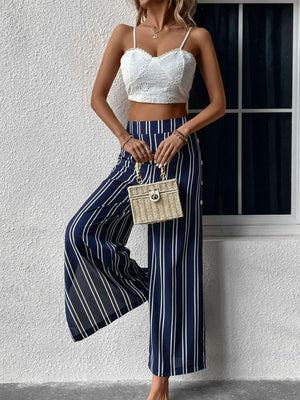 Dark blue palazzo trousers with vertical white stripes and a slit leg.