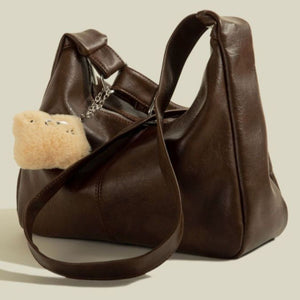 Brown pu leather crescent shoulder bag with fuzzy charm