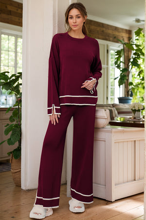 Burgundy acrylic loungewear set with round neck top and wide leg pants, featuring white trim detail.