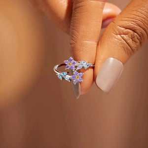 Silver ring with floral bypass design featuring purple and blue zirconia stones.