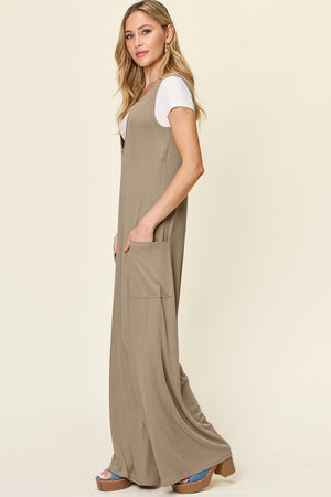 Mocha wide-leg jumpsuit with deep V-neck and front pockets, styled with a white tee.