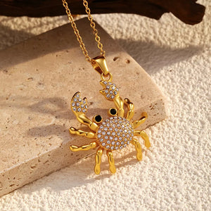 Gold-plated crab pendant necklace with crystal accents and black eyes on a delicate chain.