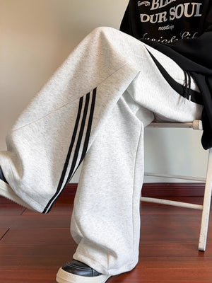 Light gray wide-leg sweatpants with black side stripes and drawstring detail