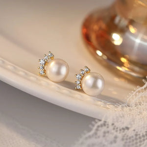 Lustrous pearl and zircon stud earrings with gold setting.