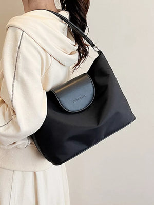 Chic black canvas hobo crossbody bag with flap closure and subtle logo detail.