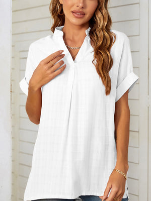 White linen blend blouse with gathered yoke, V-neck, and cuffed short sleeves.
