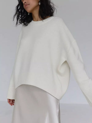 White knit sweater with ribbed detailing and crewneck, styled with a satin skirt.