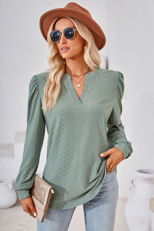 Sage green textured bishop sleeve blouse with V-neck and gathered shoulders.