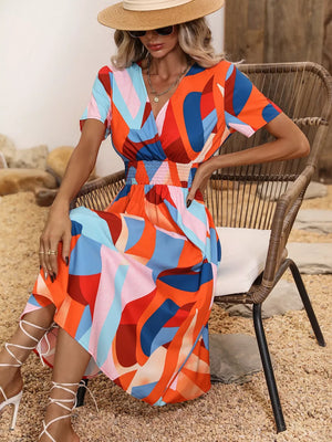 Vibrant leaf pattern midi dress with a-line cut, v-neck, short sleeves, and smocked waist.