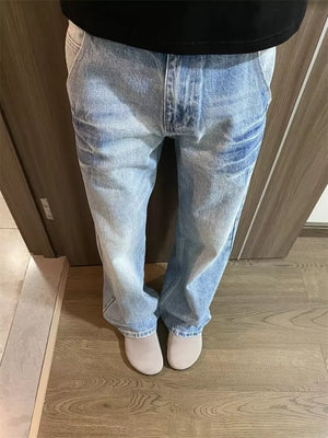Men's light wash wide-leg jeans with vintage distressing and a relaxed fit.