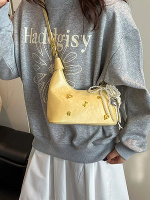 Pastel yellow hobo bag with gold accents and pearl charm detail