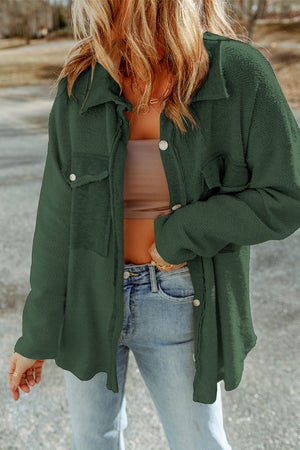 Green button-up coat with textured fabric and chest pockets.