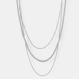 Delicate three-strand silver crystal necklace with layered chains and textured details.