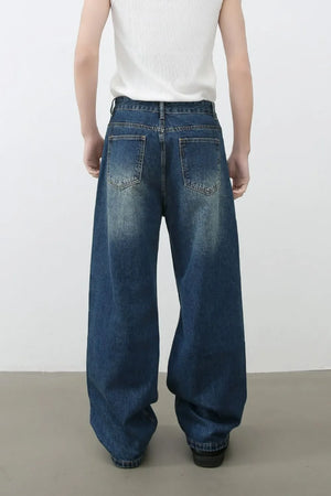 Oversized ripped denim jeans in medium wash with wide-leg silhouette and distressed details.