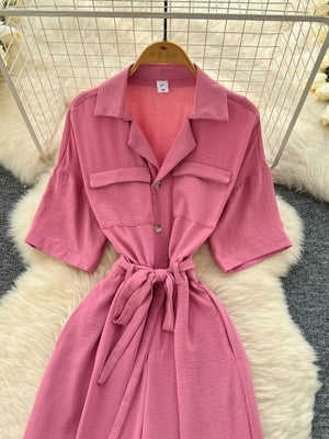 Pink belted wide-leg maternity jumpsuit with pockets and button front.
