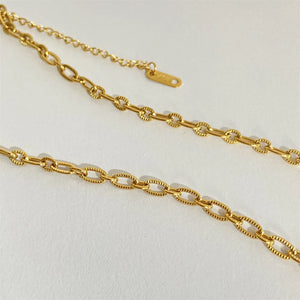 Gold sunburst medallion chain necklace with textured oval links and adjustable clasp
