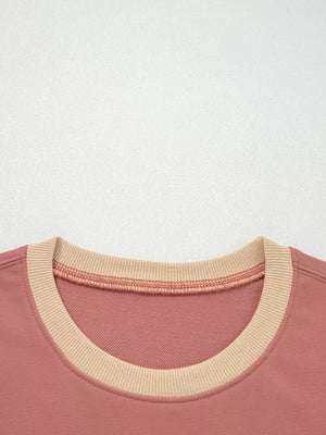 Dusty pink sweatshirt with contrast tan ribbed neckline and exposed seam detail.