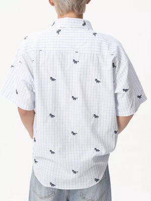 White short sleeve button up shirt with blue plaid and embroidered horse motifs.